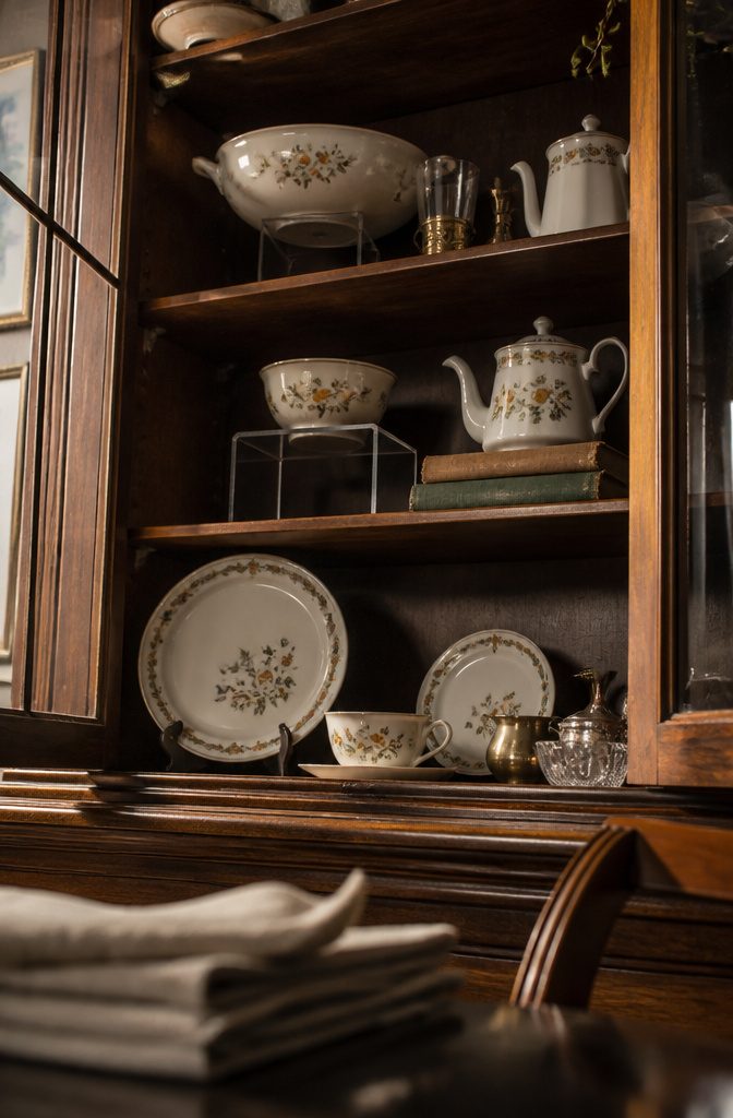 Serving bowl raised on a stand behind dishes in a china cabinet