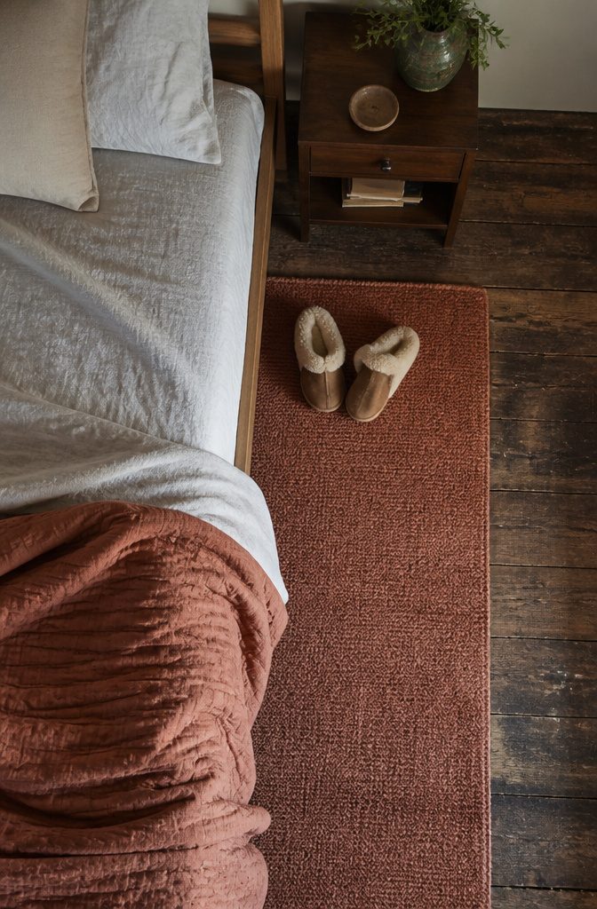 Soft bedroom rug beside the bed with textured flooring and warm furnishings