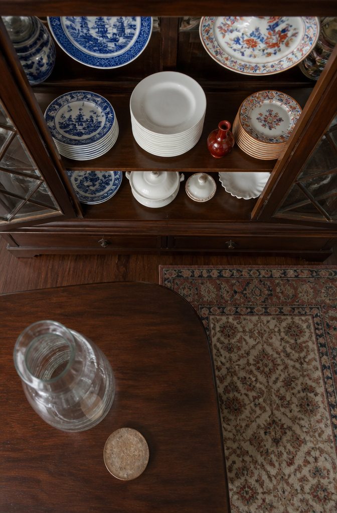 White dishes grouped between blue and colorful patterned plates in a cabinet