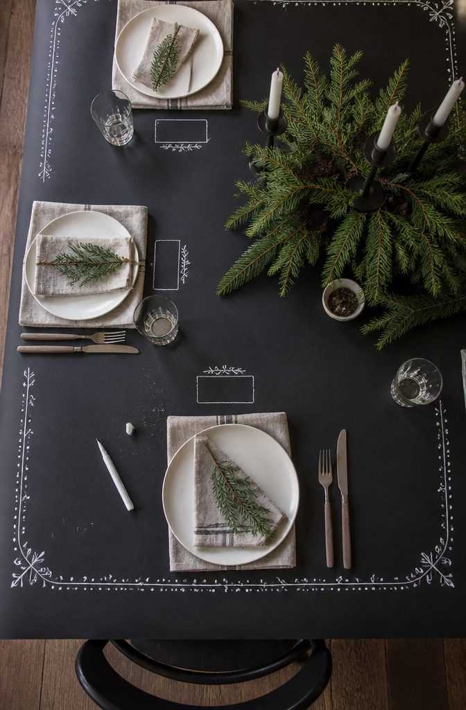 Black butcher-paper tablecloth with drawn place cards and decorative border patterns